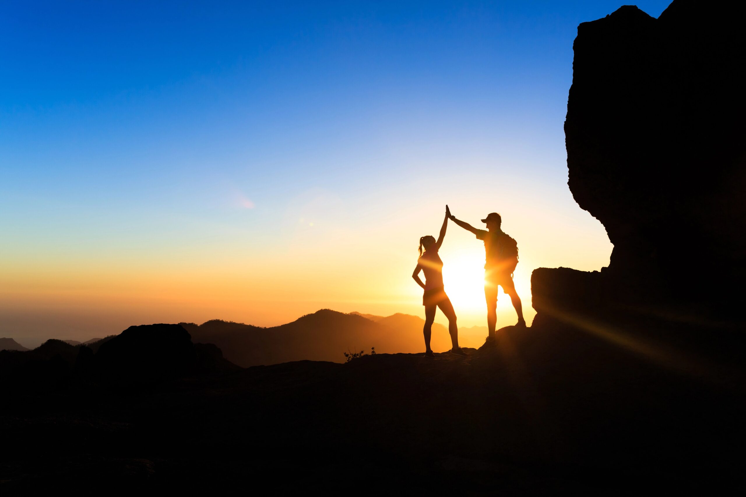 Teamwork im Sonnenuntergang oben angekommen